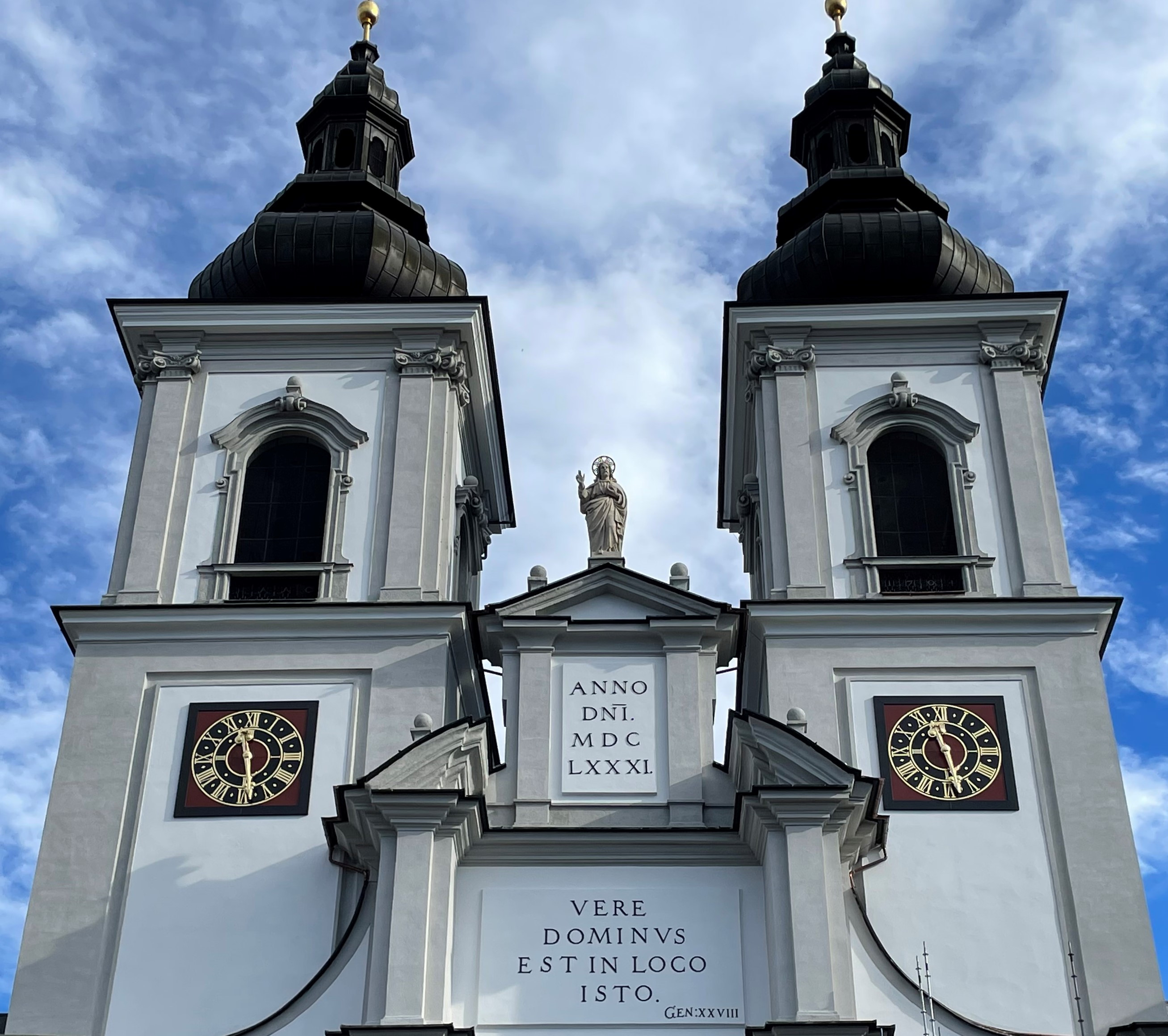 Kirchenfassade mit zwei Kirchtürmen und Christusstatue