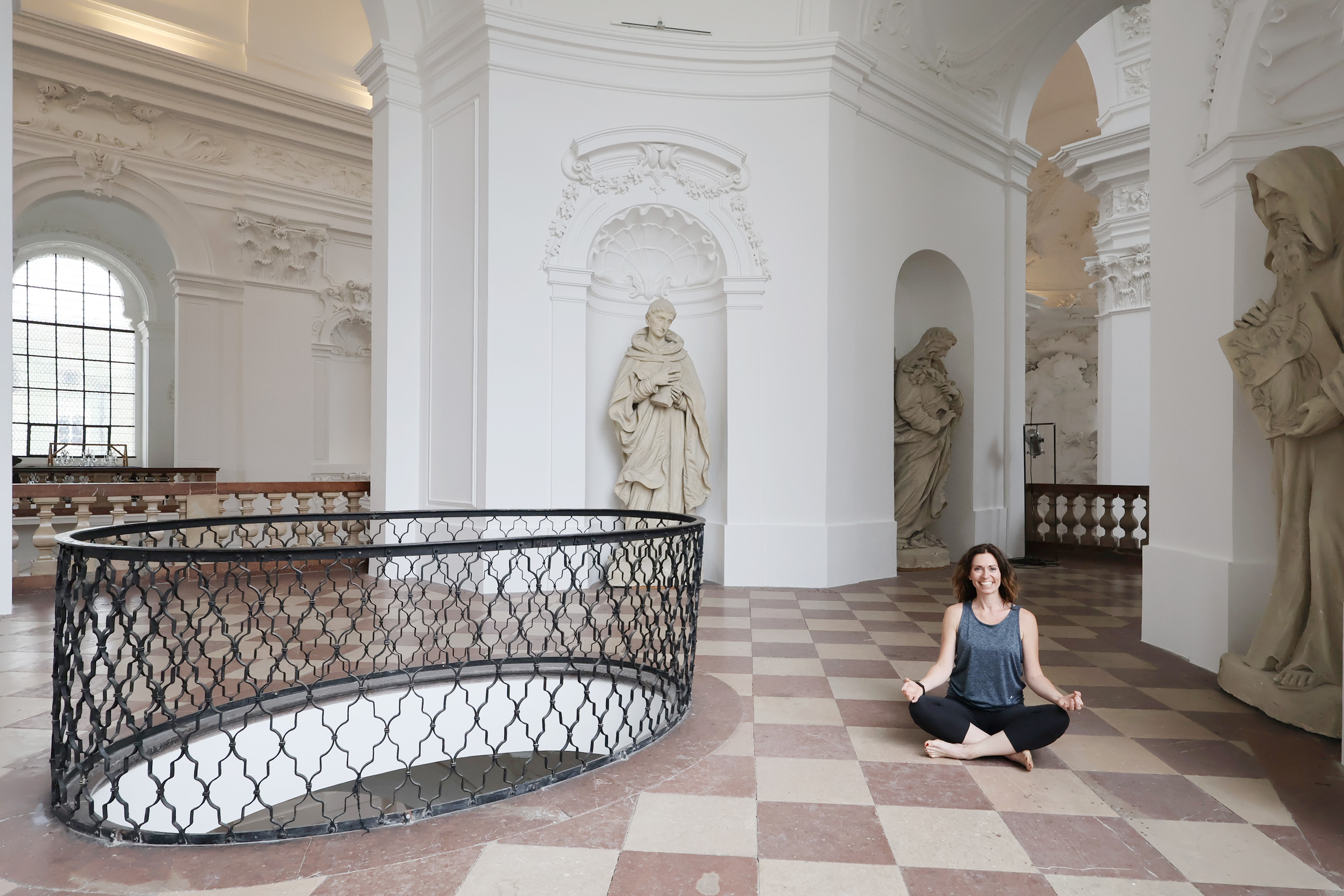 Yoga-Lehrerin Martina C. Trummer in Meditationshaltung auf der Empore der Kollegienkirche